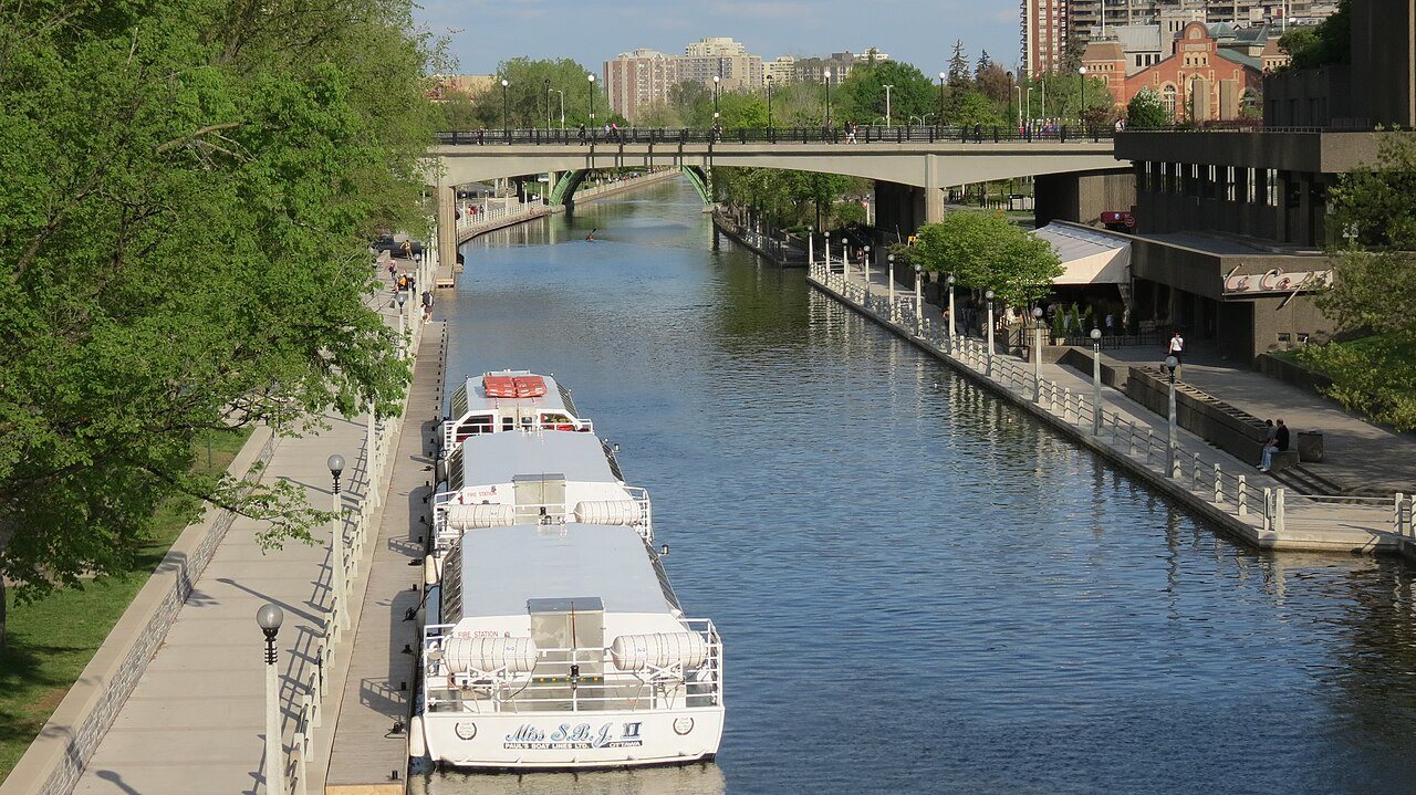Stone canal locks stepping down beside a large stone building in a city