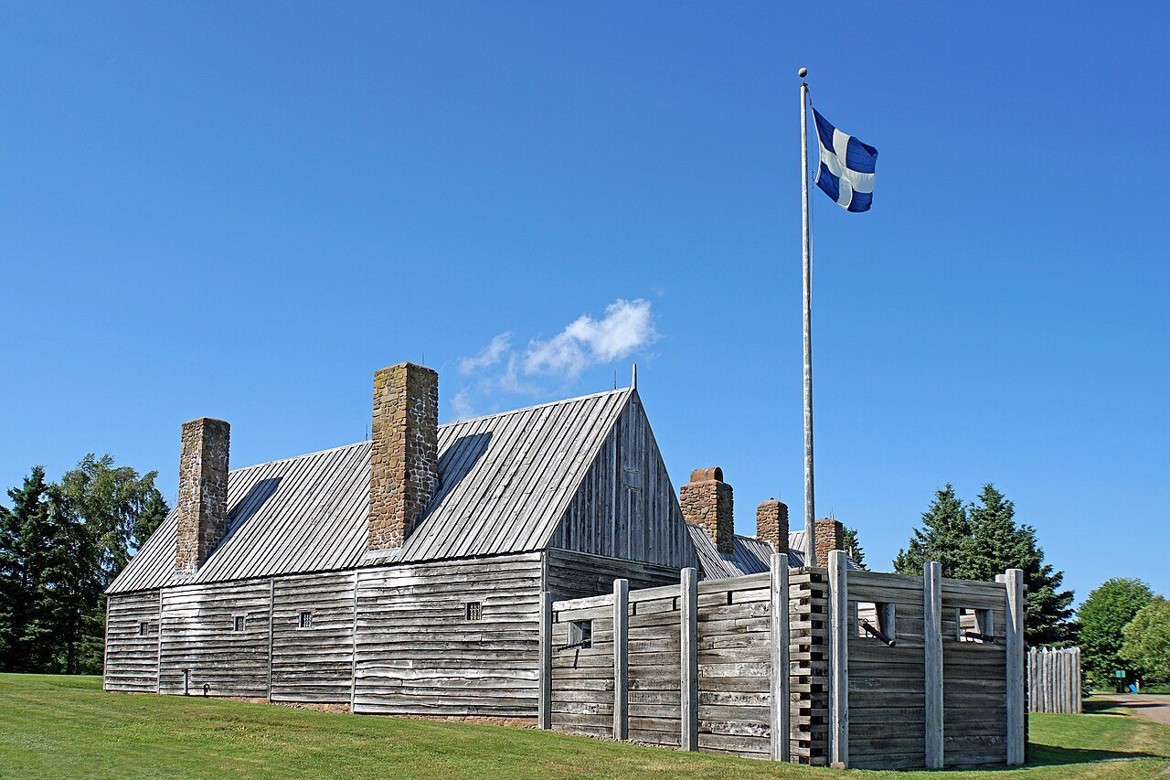 Reconstructed wooden habitation with tall chimneys and a palisade